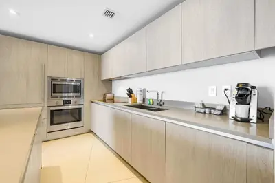 a kitchen with stainless steel appliances and wooden cabinets at Oceanfront Retreat Steps from Hollywood Beach in Hollywood