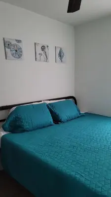 a bed with a green comforter in a room at Nassau Homestay in Opa-locka