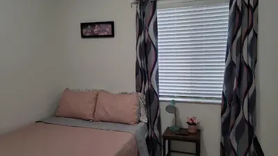 a small bedroom with a bed and a window at Nassau Homestay in Opa-locka