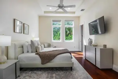 a white bedroom with a bed and a flat screen tv at New Luxe Super Villa by The Glam Homes in Plantation