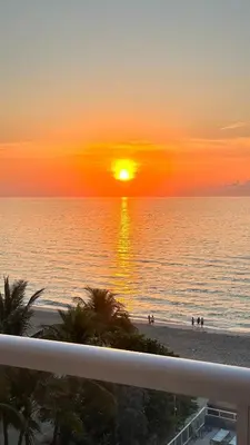 a sunset on the beach with people on the beach at Sunny Isles Oceanfront Apartment for Two in Sunny Isles Beach