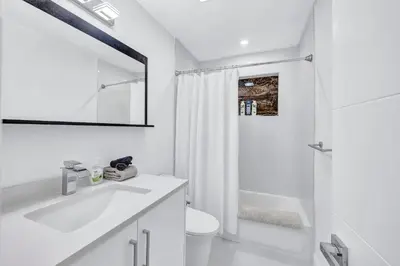 a white bathroom with a sink and a shower at Trendy Waterfront Pool Home Beach Casino Airport in Hollywood