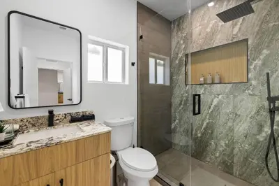 a bathroom with a toilet and a shower with a mirror at Luxury 4BR Retreat | Pool • Kitchen in Goulds
