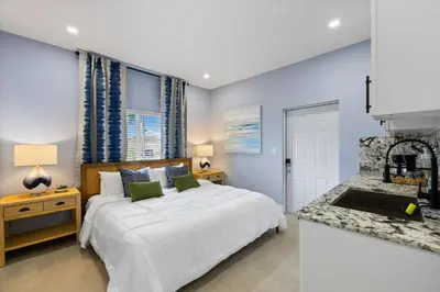 a bedroom with a white bed and a kitchen at Luxury 4BR Retreat | Pool • Kitchen in Goulds