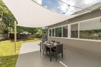 a patio with a table and chairs under a white umbrella at Casa Moderna 3 Bed 2 Bath with Private Patio and BBQ in North Miami Beach