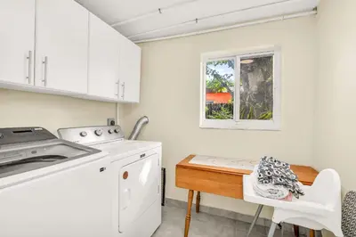 a kitchen with white cabinets and a table and a window at Backyard Oasis 3 Hole Golf Pool Fire Pit in Fort Lauderdale