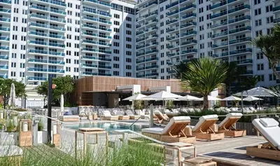 a pool with lounge chairs and umbrellas and buildings at Amazing View 1 Hotel Corner Unit 1BR/1BA w Balcony in Miami Beach