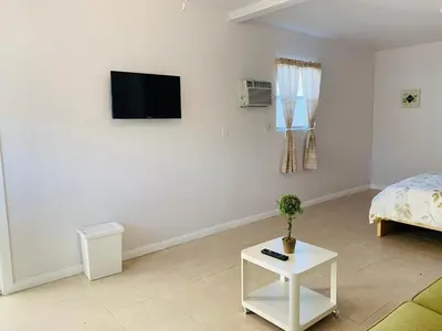 a white room with a bed and a tv on the wall at Zen Garden Studio in Hollywood