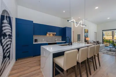 a kitchen with blue cabinets and a bar with chairs at The Avenue Hotel Coral Gables in Miami