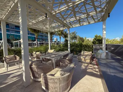 a patio with a table and chairs under a pergola at Luxury View-Walk to beach! in Miami Beach