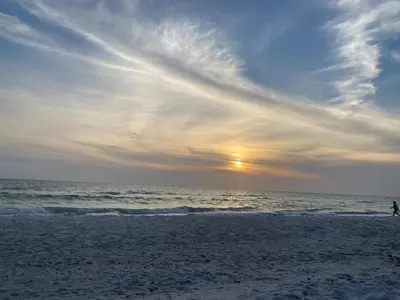 a person walking on the beach at sunset at Luxurious 2BD Condo with Direct Ocean Views & Resort Pool in Sunny Isles in Sunny Isles Beach