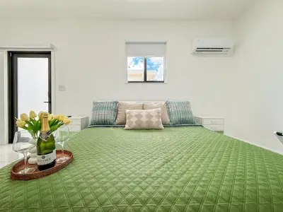 a bedroom with a green bed with a vase of flowers at Luxury Suite Studio with Kitchen & Spa Shower in Miramar