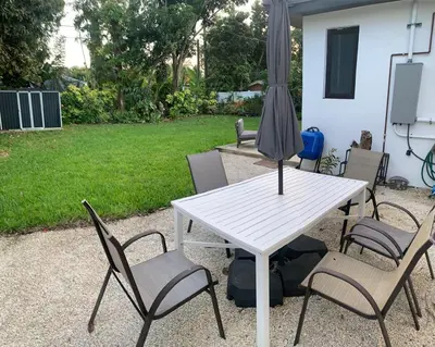 a white table with chairs and an umbrella at MIAMi MID-CENTURY GEM in North Miami Beach