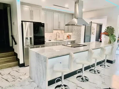 a kitchen with white cabinets and a counter with stools at MIAMi MID-CENTURY GEM in North Miami Beach