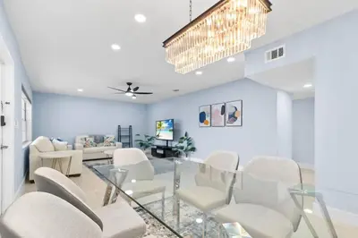 a dining room with white chairs and a chandelier at Las Olas & Beachside getaway with pool in Fort Lauderdale