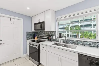 a kitchen with white cabinets and a sink and a window at Beach Pool & Las Olas Getaway Fort Lauderdale in Fort Lauderdale