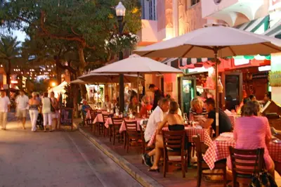 a group of people sitting at tables under umbrellas on a street at Best Location In South Beach Steps To Everything! in Miami Beach