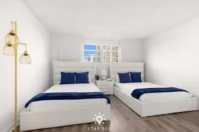 two beds in a white room with blue pillows at Modern Hollywood Beach Escape - City Views in Hollywood
