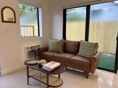 a living room with a brown couch and a table at The Modern Oasis Queen Studio with Kitchen in Fort Lauderdale
