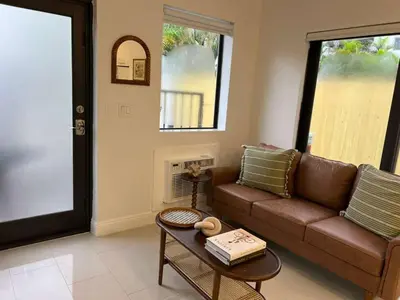 a living room with a brown couch and a table at The Modern Oasis Queen Studio with Kitchen in Fort Lauderdale