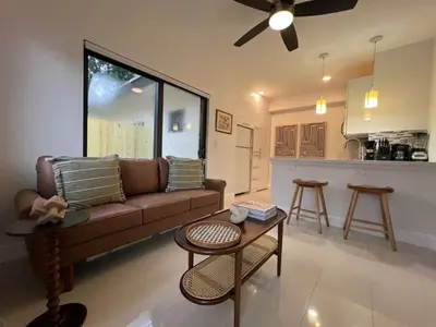 a living room with a couch and a table and a kitchen at The Modern Oasis Queen Studio with Kitchen in Fort Lauderdale