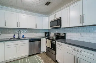 a kitchen with white cabinets and black counter tops at Jungle Fortress in Fort Lauderdale