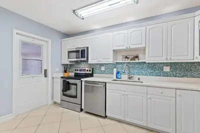 a kitchen with white cabinets and a sink at Beachside Las Olas Getaway Oasis with Pool in Fort Lauderdale