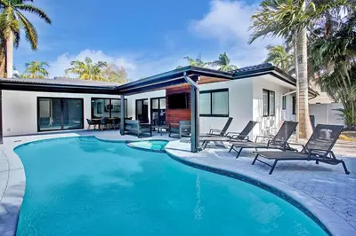 a swimming pool with chairs and a house at Coral Lane by Rove Travel - Home with Pool & BBQ in Fort Lauderdale