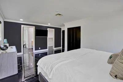 a bedroom with a large white bed and a bathroom at Coral Lane by Rove Travel - Home with Pool & BBQ in Fort Lauderdale
