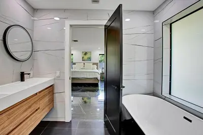 a bathroom with a tub and a sink and a mirror at Coral Lane by Rove Travel - Home with Pool & BBQ in Fort Lauderdale