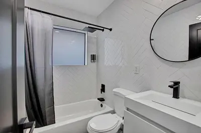 a bathroom with a toilet and a sink and a mirror at Coral Lane by Rove Travel - Home with Pool & BBQ in Fort Lauderdale