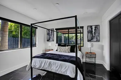 a bedroom with a canopy bed and windows at Coral Lane by Rove Travel - Home with Pool & BBQ in Fort Lauderdale