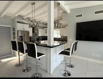 a kitchen with a bar with chairs and a flat screen tv at Miami Lifestyle, Modern, Private heated Pool, BBQ in North Miami Beach