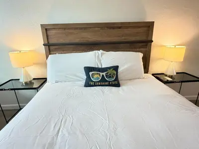 a bed with a pillow on it with two lamps at Sunny Miami Beach Getaway , Steps from the Ocean! in Miami Beach