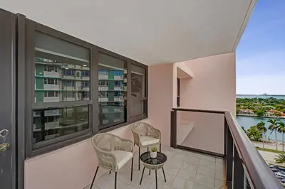 a balcony with two chairs and a table and some windows at Stylish 3BR Retreat Steps from the Beach with Resort Amenities 1508 in Miami Beach