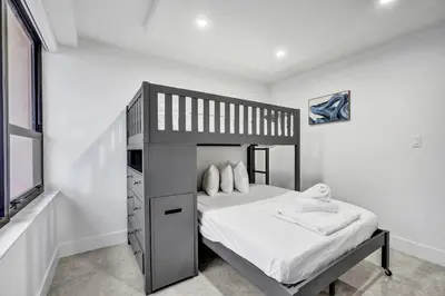 a bedroom with a bunk bed with white sheets at Modern 3BR Ocean view Condo with Pools, Gym and Sauna 1407 in Miami Beach