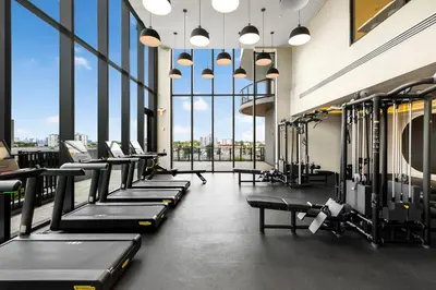 a gym with rows of tread machines and large windows at 72 Park Condo - City Views & Prime Location in Miami Beach