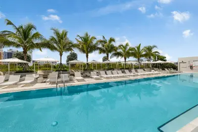 a swimming pool with lounge chairs and palm trees at 72 Park Condo - City Views & Prime Location in Miami Beach