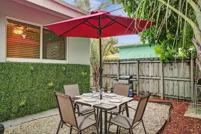 a table with a red umbrella in a backyard at Casa Sol A in Fort Lauderdale