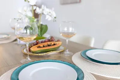 a table with plates and glasses of wine on it at 1-Bedroom Apartment with Ocean View and Balcony near Sunny Isles Beach in Sunny Isles Beach