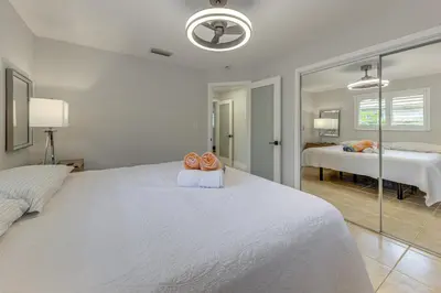 a white bedroom with a large bed and a mirror at Walkable Island City Oasis with Private Heated Pool! in Fort Lauderdale
