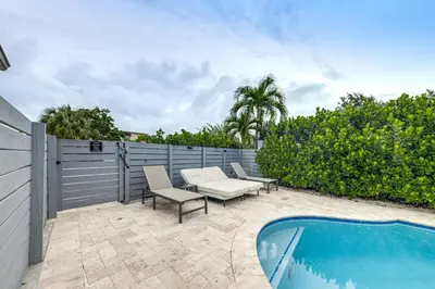 a patio with two chairs and a swimming pool at Walkable Island City Oasis with Private Heated Pool! in Fort Lauderdale