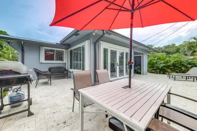a picnic table with a red umbrella on a patio at Walkable Island City Oasis with Private Heated Pool! in Fort Lauderdale
