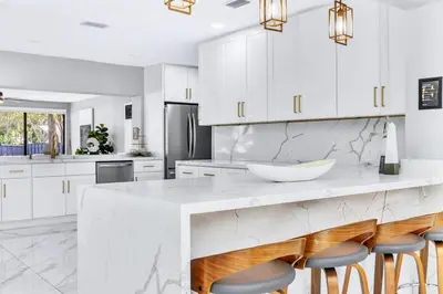 a kitchen with white cabinets and a large island with bar stools at Riverbend Yacht Retreat Waterfront Villa with Pool in Fort Lauderdale