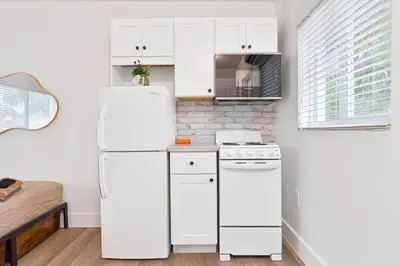 a white kitchen with a refrigerator and a stove at Miami Modern Studio minutes to Wynwood & Downtown in Miami