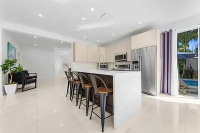 a kitchen with white cabinets and black chairs and a counter at Renovated house w private heated pool grill in Hollywood