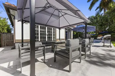 a patio with a table and chairs and umbrellas at Renovated house w private heated pool grill in Hollywood