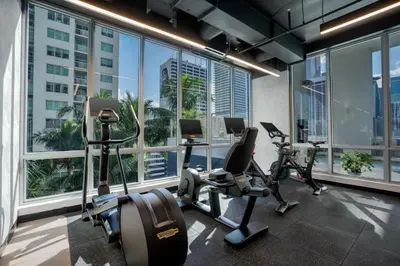 a gym with cardio equipment in a building with windows at CAL KING BED Downtown Miami Free Parking Pool Gym in Miami