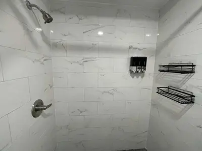 a bathroom with a shower with white marble walls at KING OF MIAMI - 2bd Retreat 1 mile from Brickell in Miami