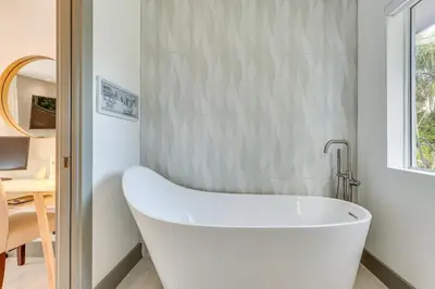 a white bath tub in a bathroom with a table at Relax in the Sun! Gem 1 Mi to Las Olas Beach in Fort Lauderdale